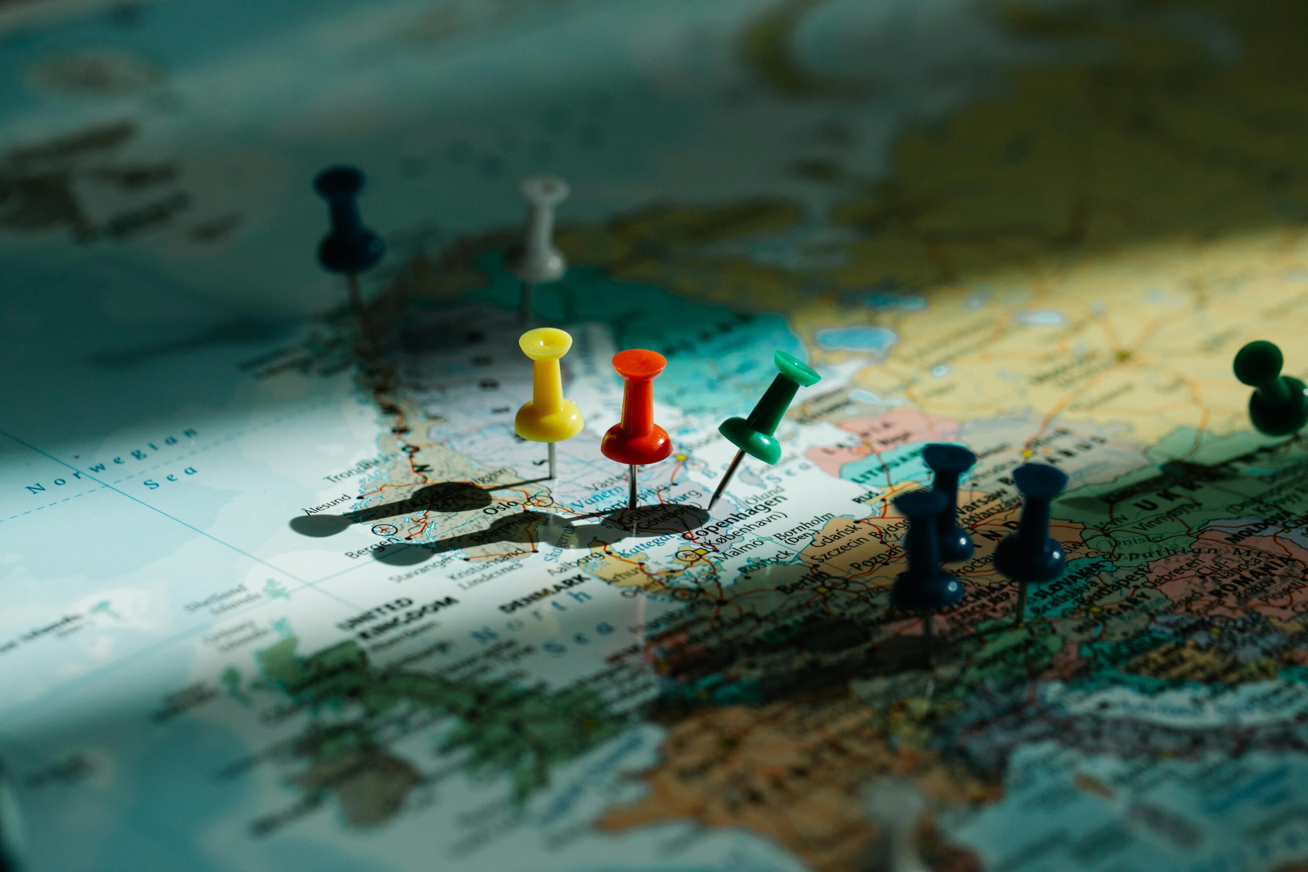 A close-up view of colorful push pins marking locations on a detailed world map.